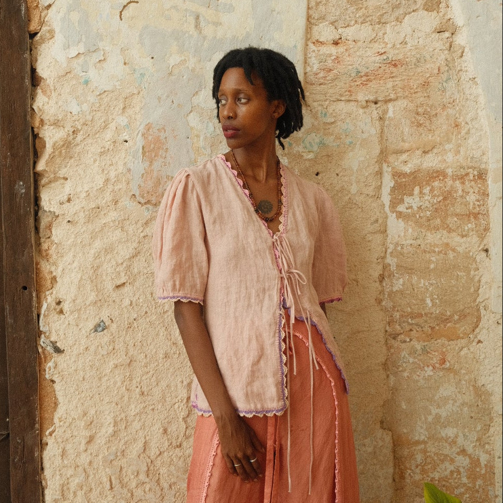 Woman lying on a bed with a textured wall and wooden headboard in the background