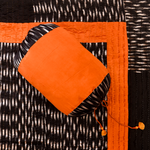 Orange fabric with black and white pattern on a textured black and white background